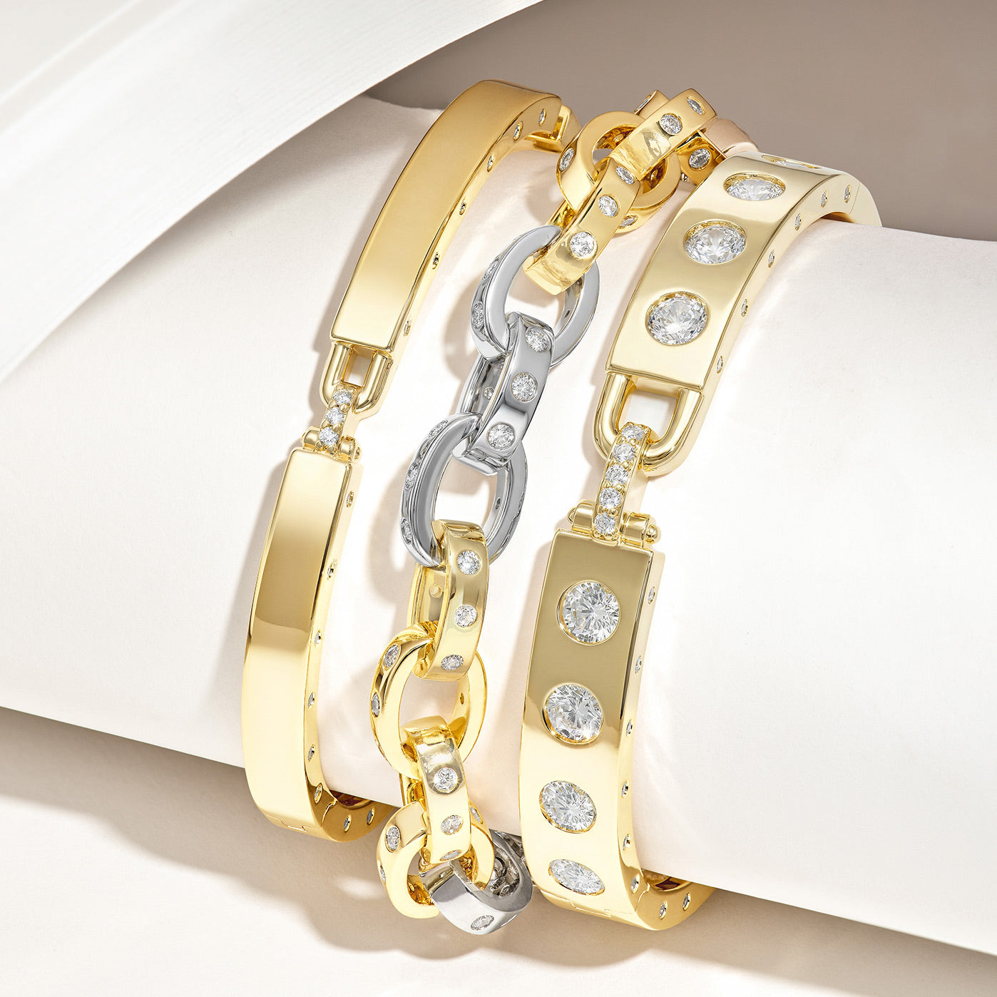 Three gold bracelets with diamond accents on a white surface