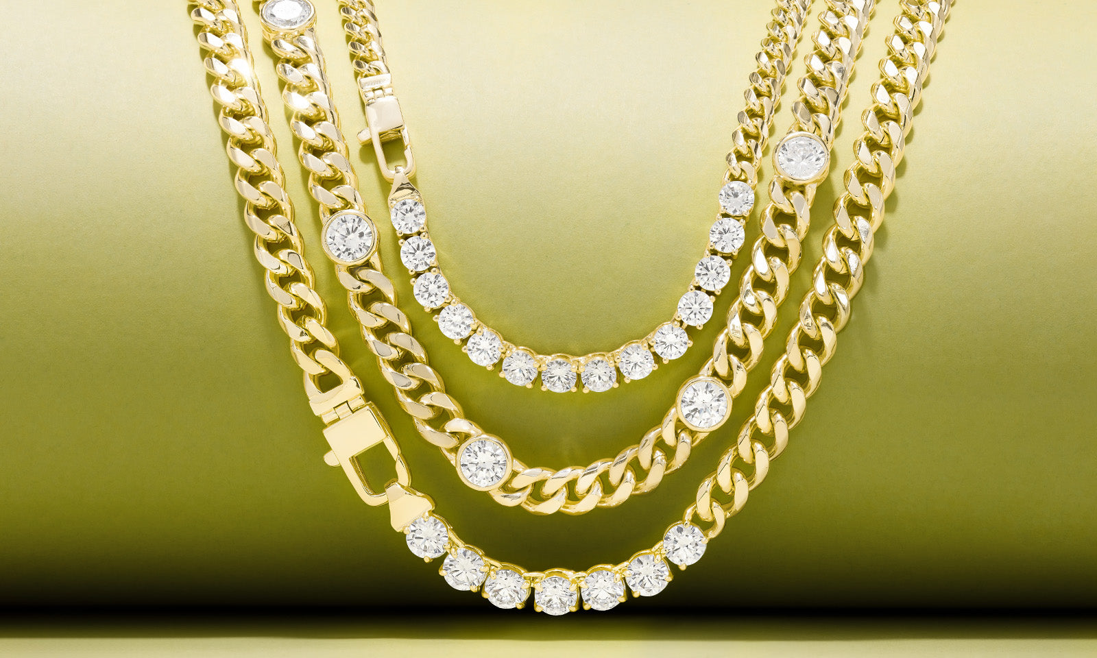 Julian Chain Necklaces draped on a green background.