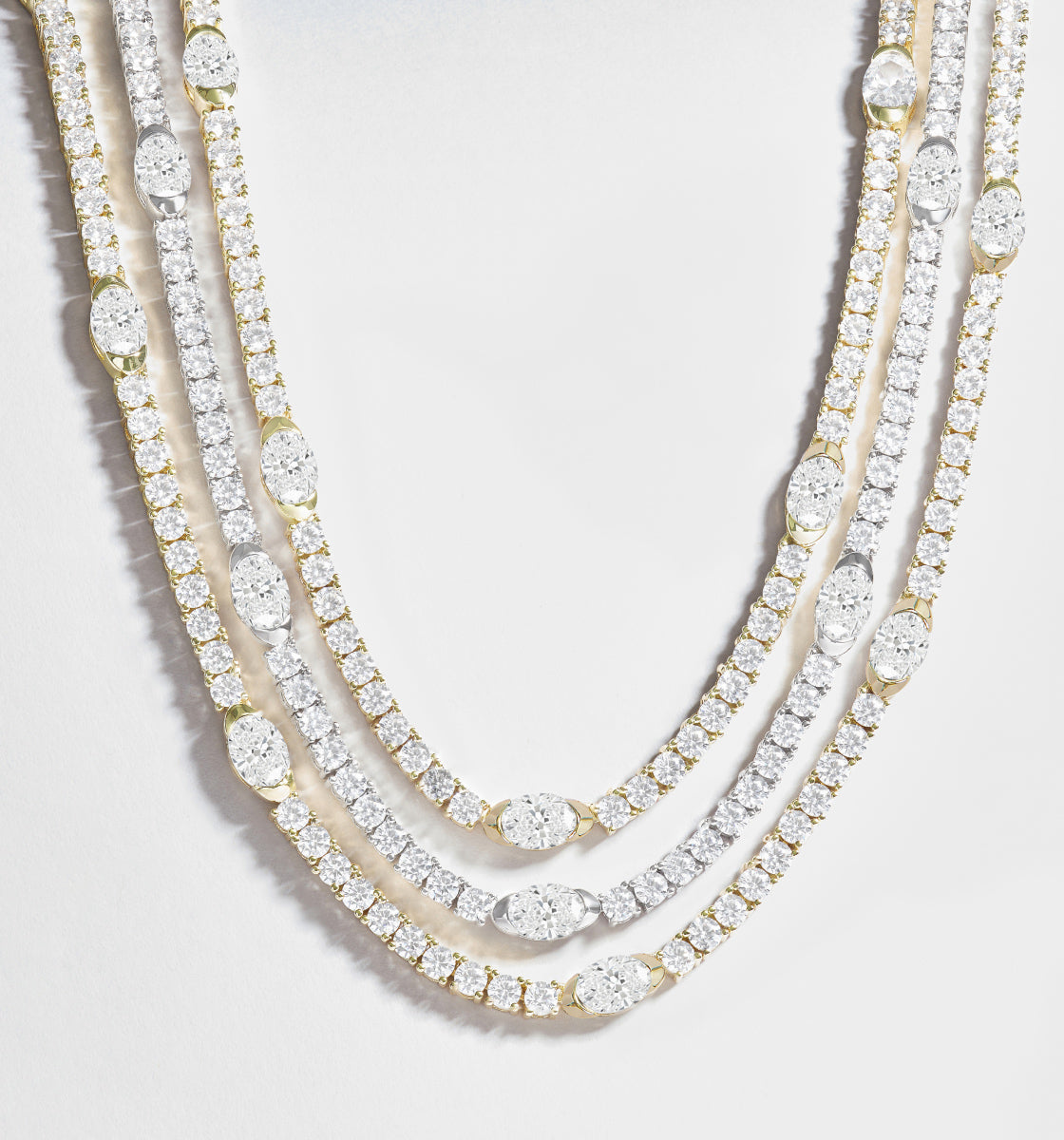 Three diamond necklaces on a light gray background