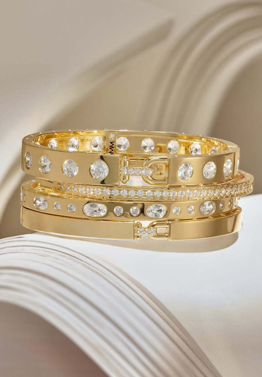 Gold bracelets with diamond accents on a textured surface