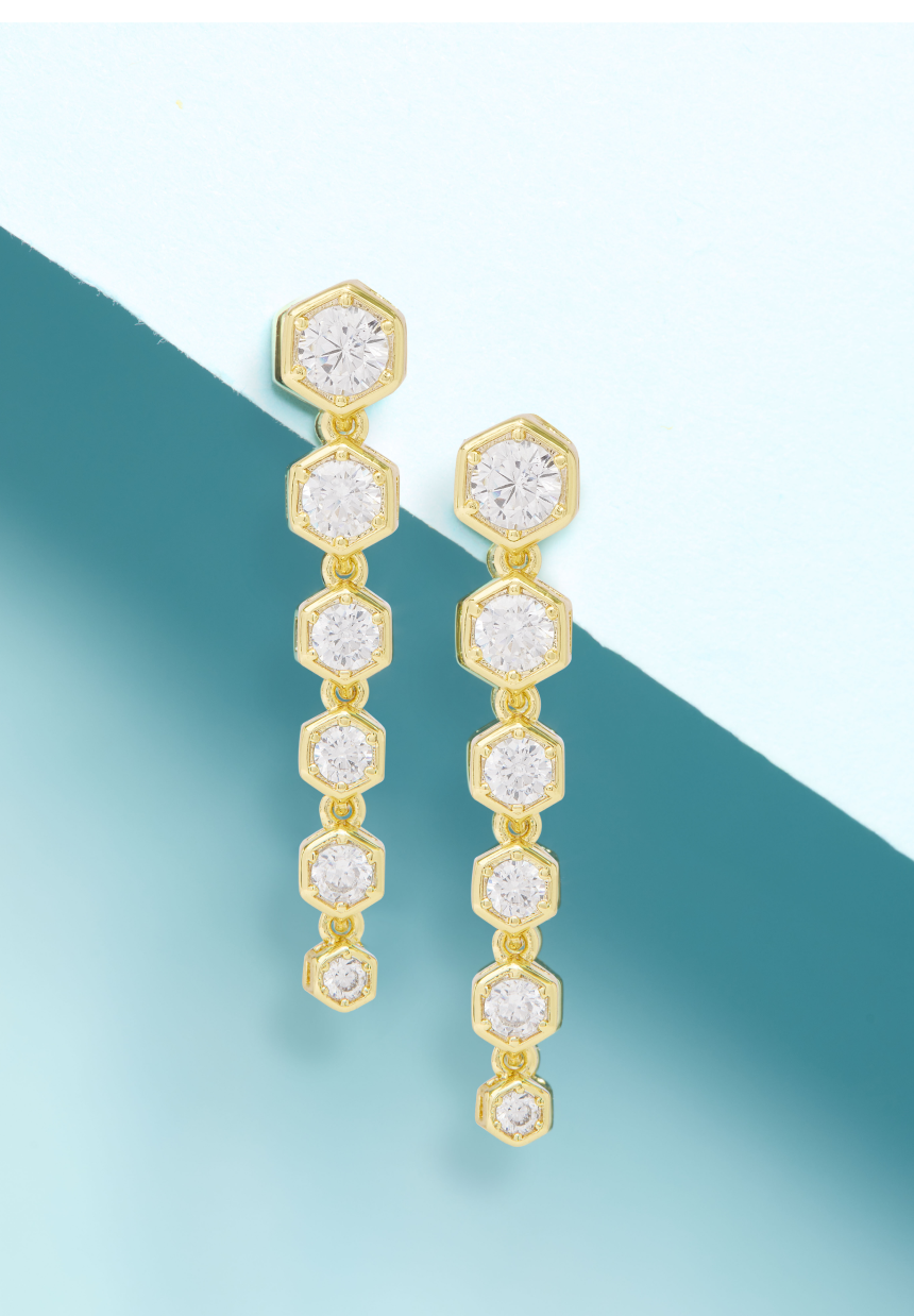 Gold earrings with clear gemstones on a gradient blue background