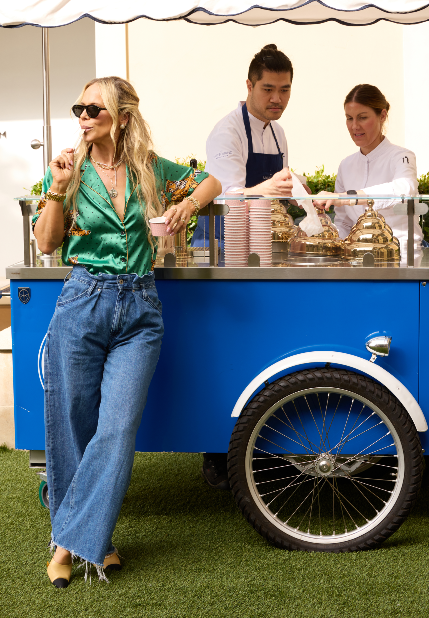 Woman leaning against a blue food cart with two people behind it.