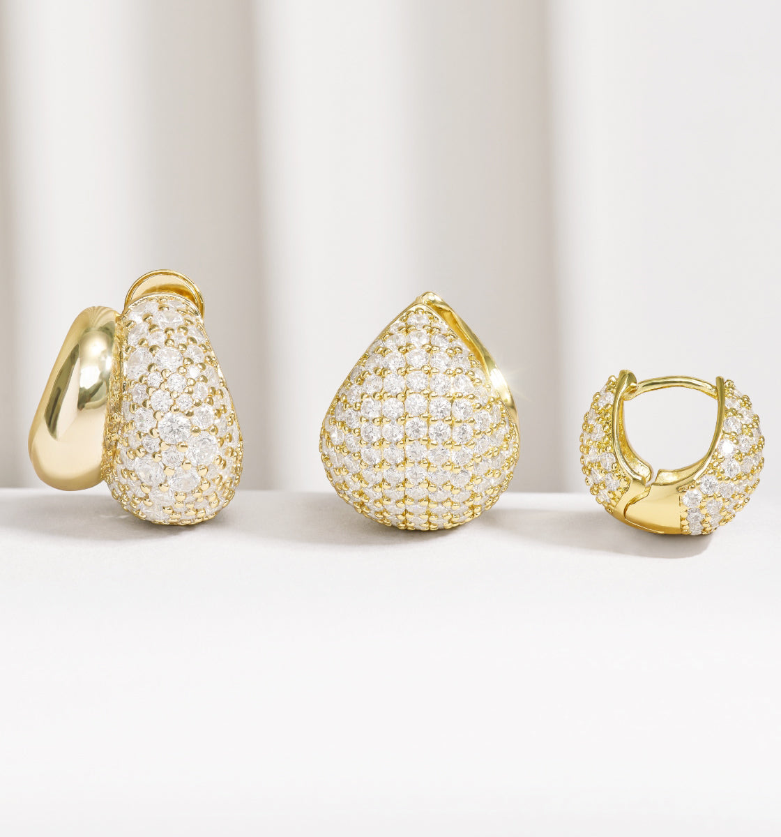 Gold earrings with diamond accents on a light background