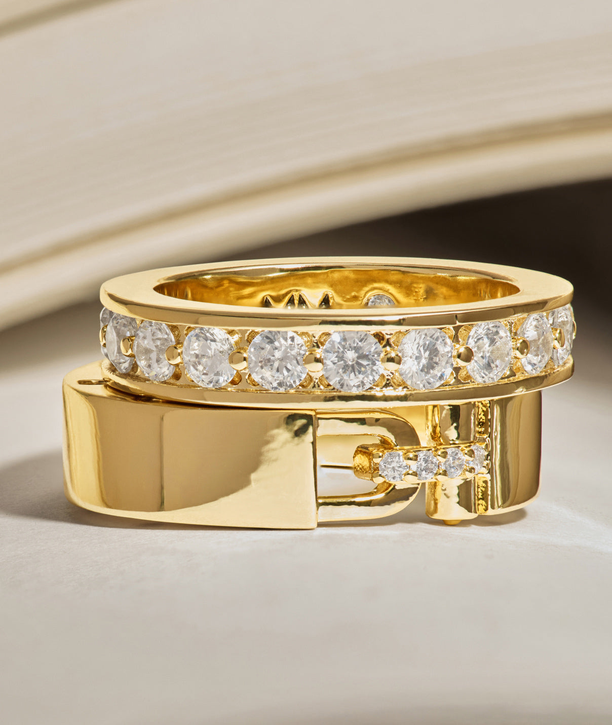 Gold ring with diamond accents on a beige background