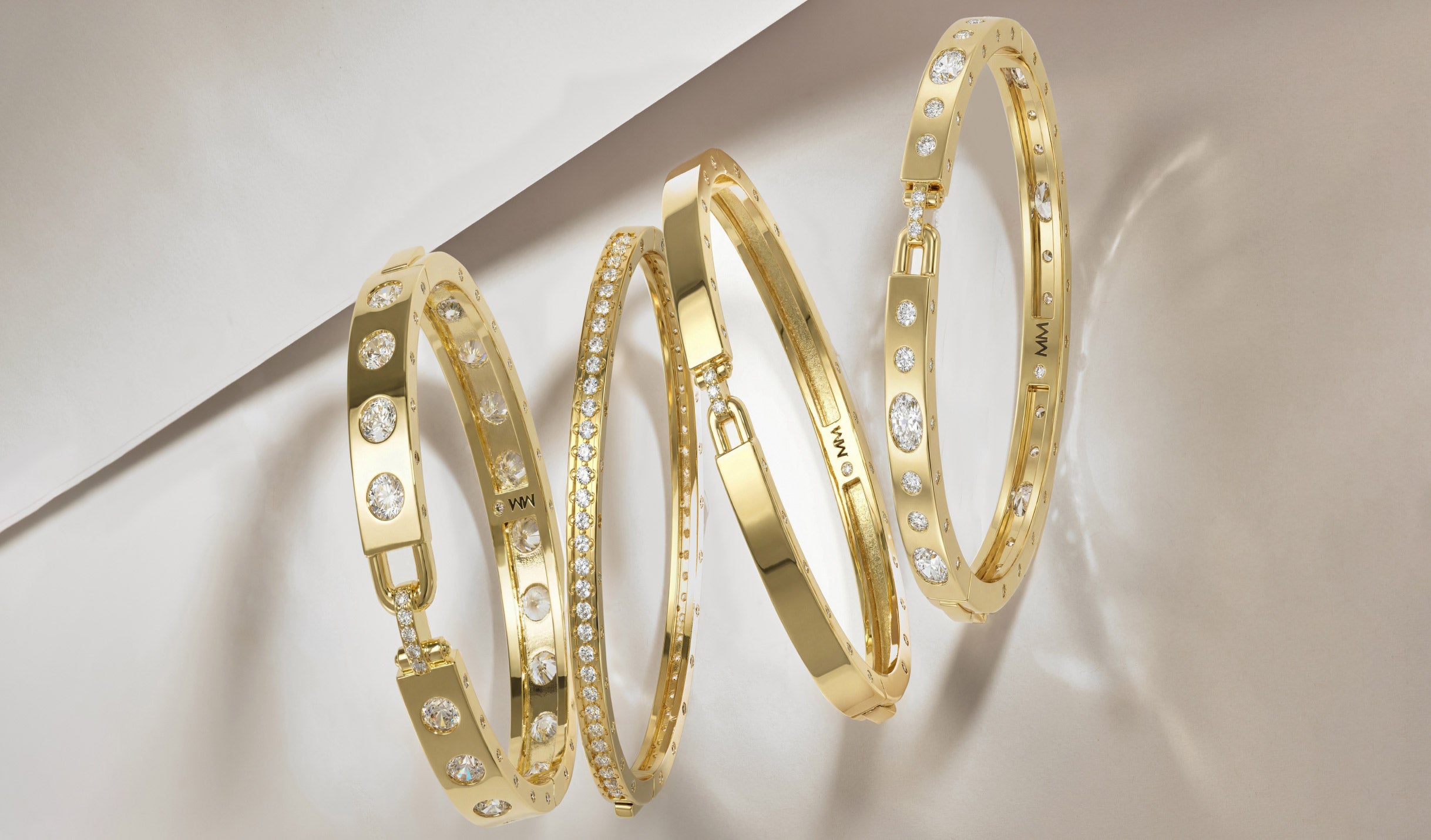 Three gold bracelets with diamond accents on a light background