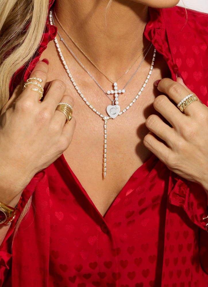 Person wearing a red garment with a necklace featuring a cross and heart pendant.