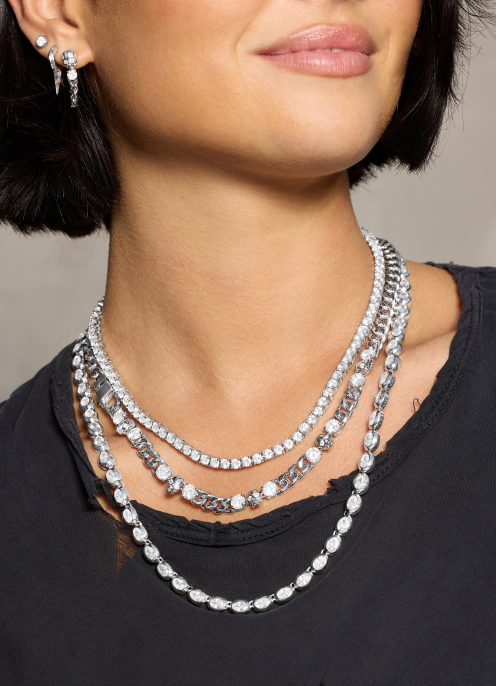 Close-up of a woman wearing a silver necklace and earrings against a neutral background
