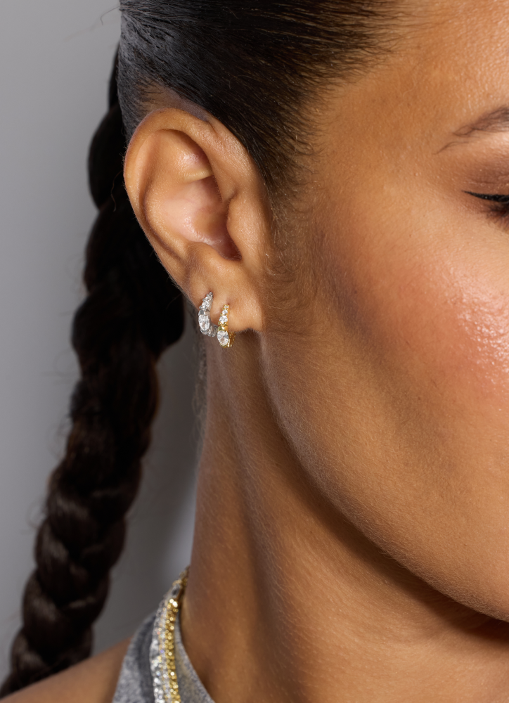 Close-up of an ear with a diamond earring against a neutral background
