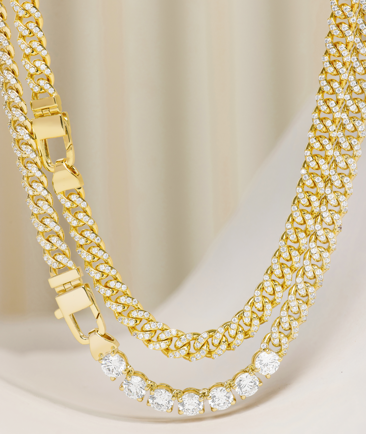 Two gold necklaces with diamond accents on a beige background