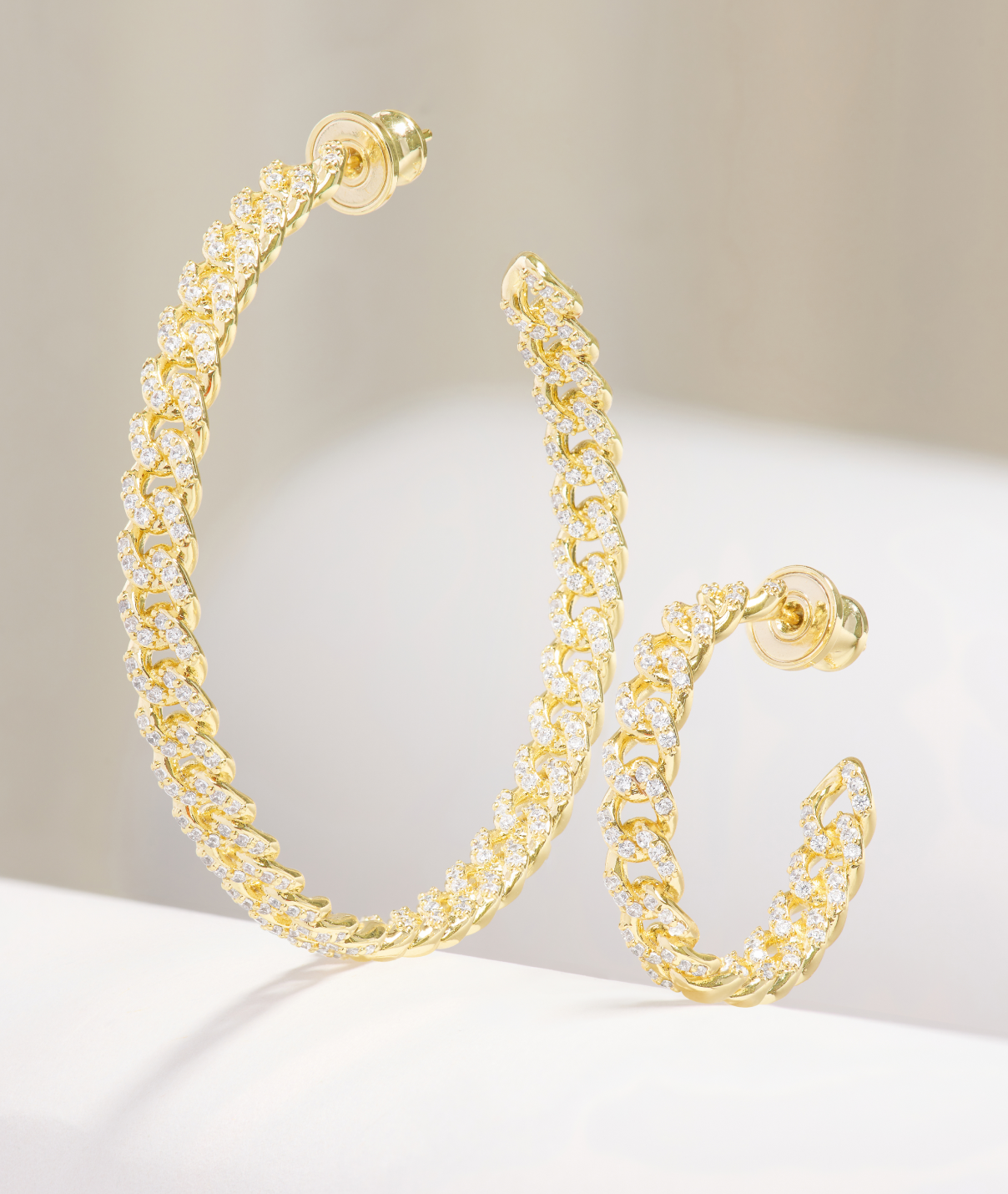 Gold chain hoop earrings on a light background