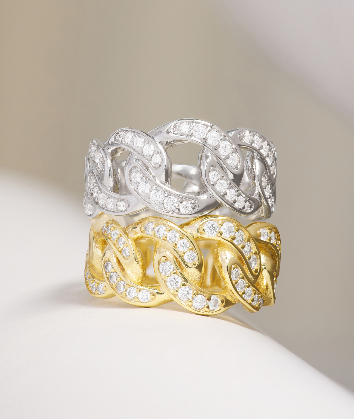 Two intertwined rings, one silver and one gold, on a neutral background