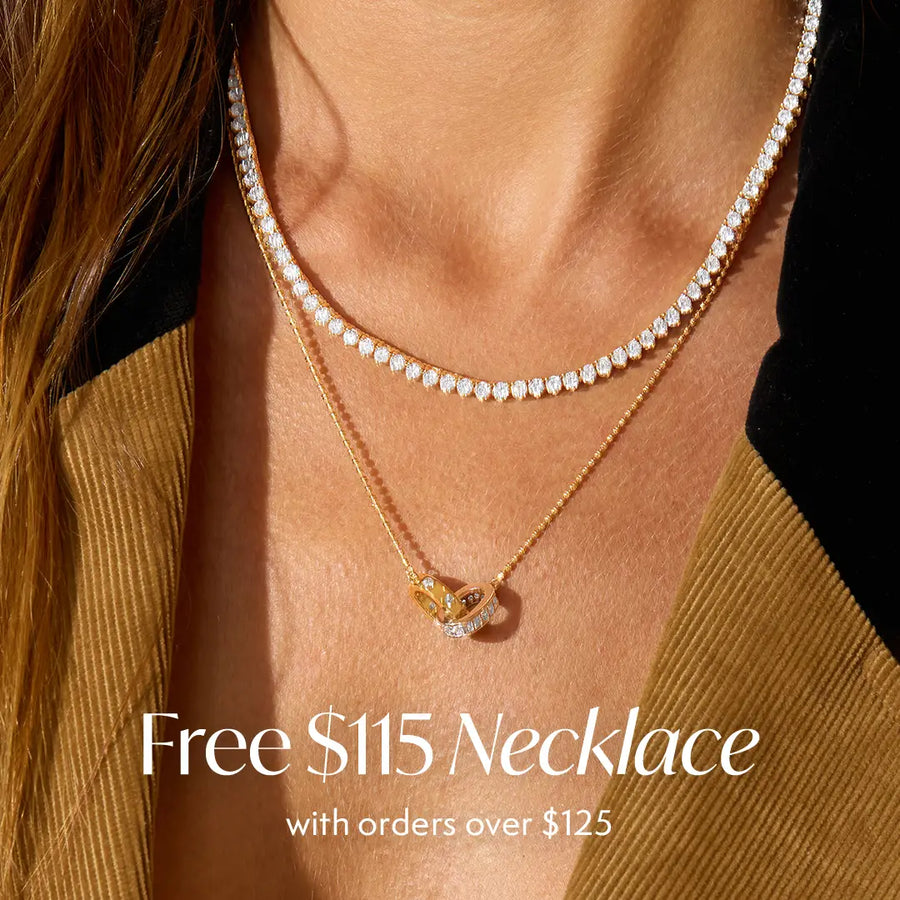A close-up of a model's neck wearing two delicate necklaces: a double-row diamond tennis necklace and a gold chain with an interlocking pendant. White text at the bottom reads 'Free $115 Necklace with orders over $125'.