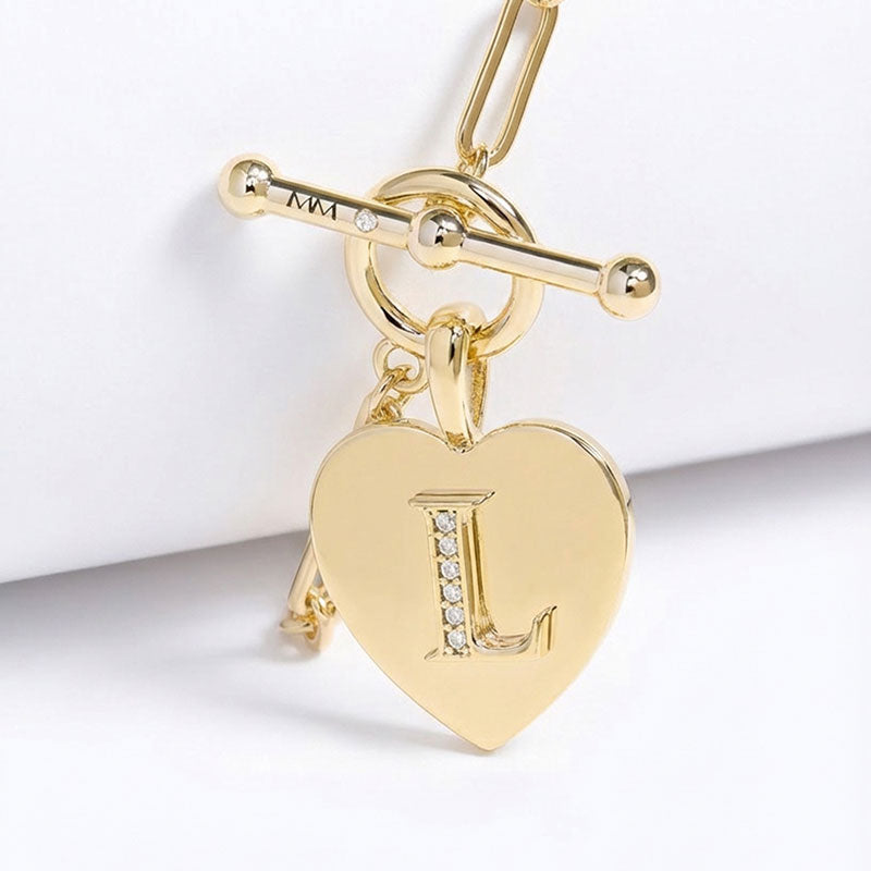 Gold heart-shaped charm with letter 'L' on a white background