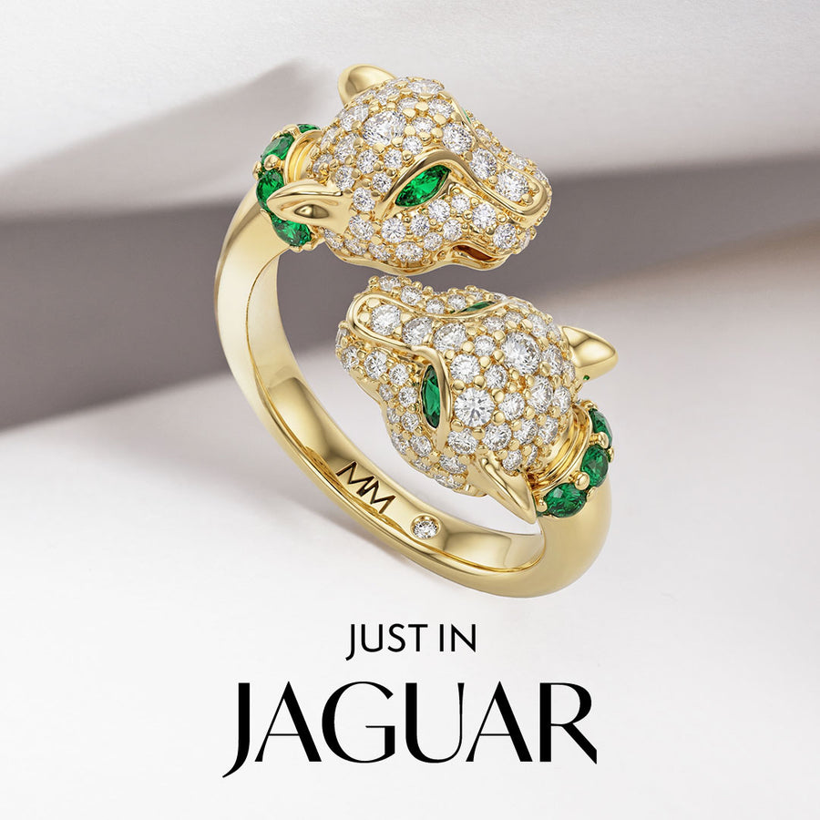 Gold Jaguar ring with emerald eyes on a light background.