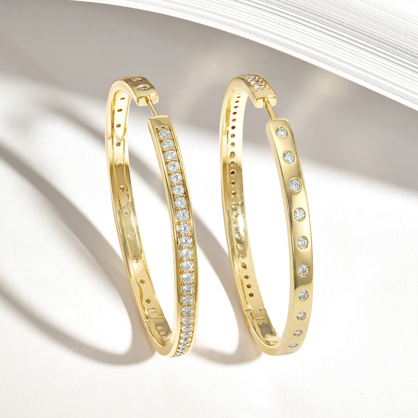 Gold hoop earrings with embedded diamonds on a light background