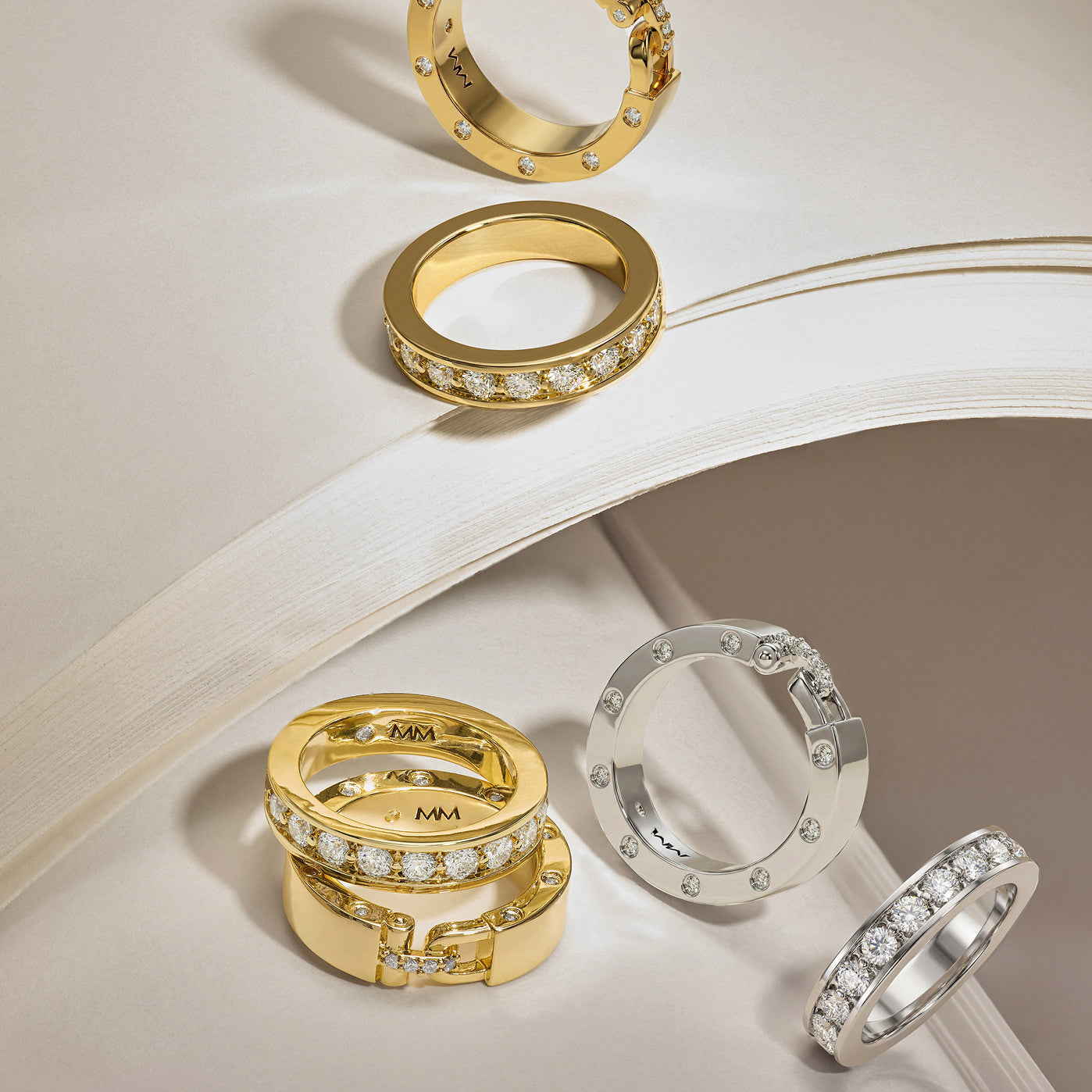 Gold and silver rings with diamond accents on a textured surface