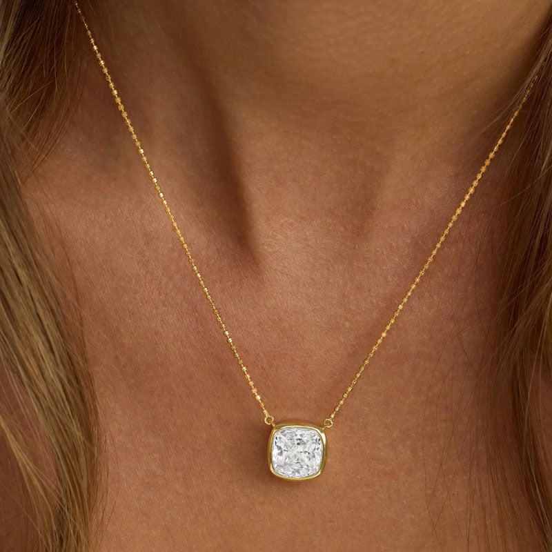 Gold necklace with a square pendant on a person's neck