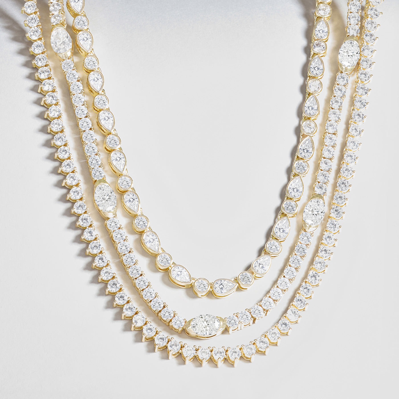 Two gold necklaces with clear gemstones on a light gray background