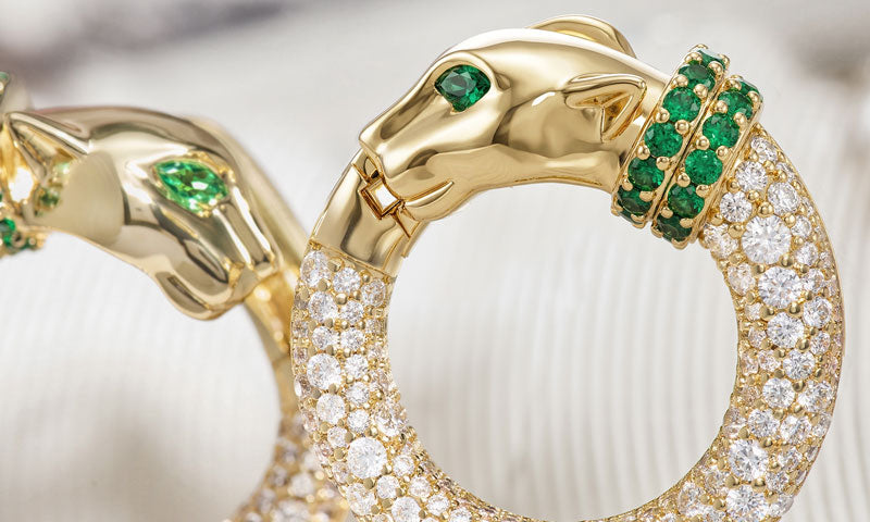 Gold bracelet with emerald and diamond accents on a white background