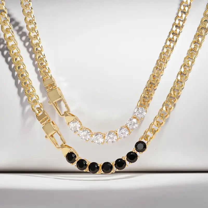 Two gold-tone chain necklaces displayed on a white background. The top necklace features a curved row of clear round stones, while the bottom necklace has a matching curved row of round black stones.