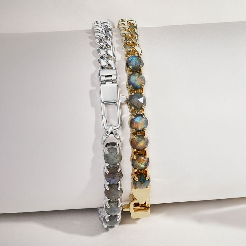 Two bracelets, one silver and one gold, on a white surface