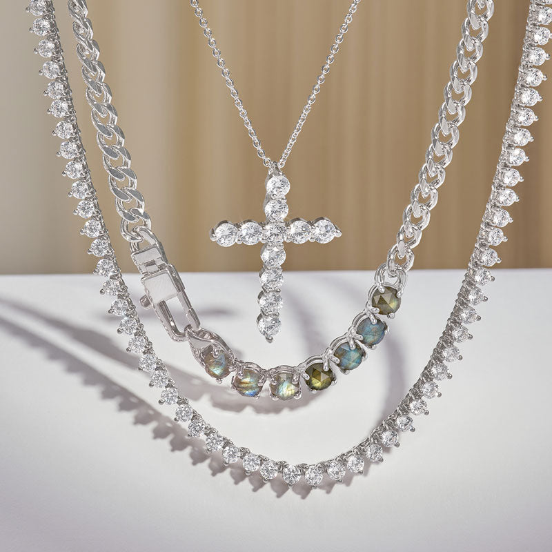 Silver jewelry set with a cross pendant on a neutral background