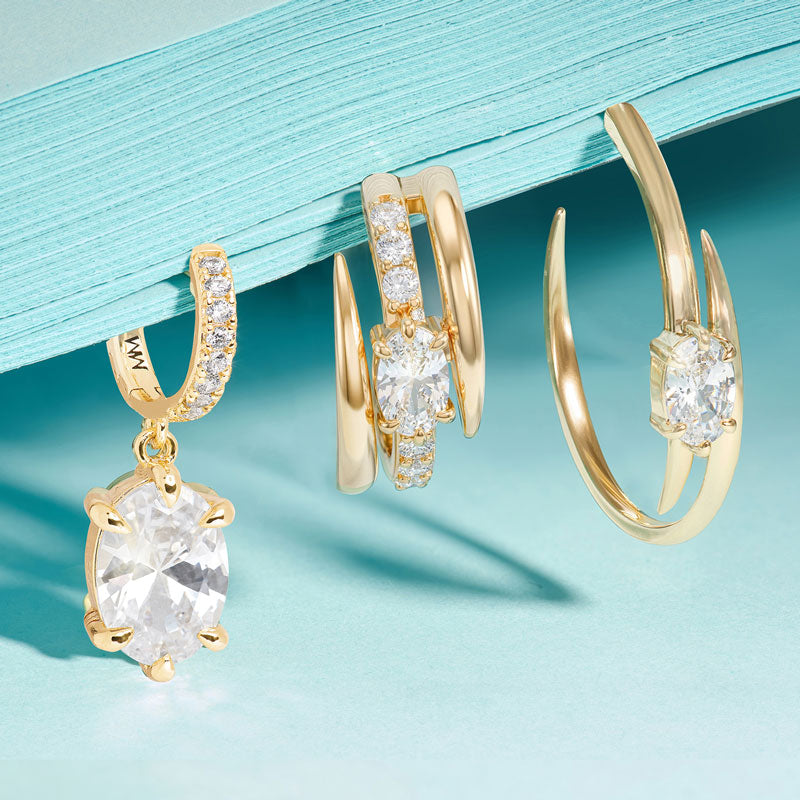 Gold hoop earrings with clear gemstones on a light blue background