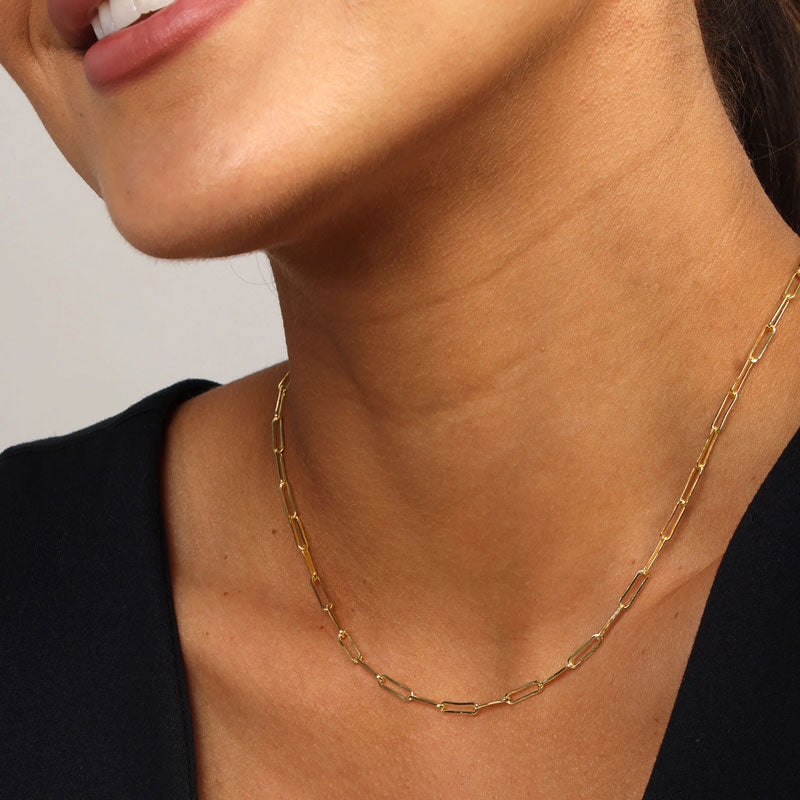 Gold necklace worn by a person against a neutral background