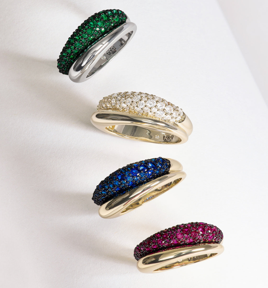 Four rings with gemstone accents on a white background