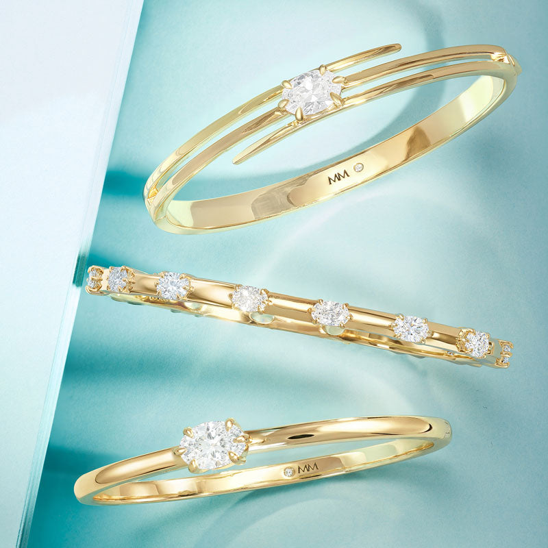 Gold bracelets with diamond accents on a light blue background