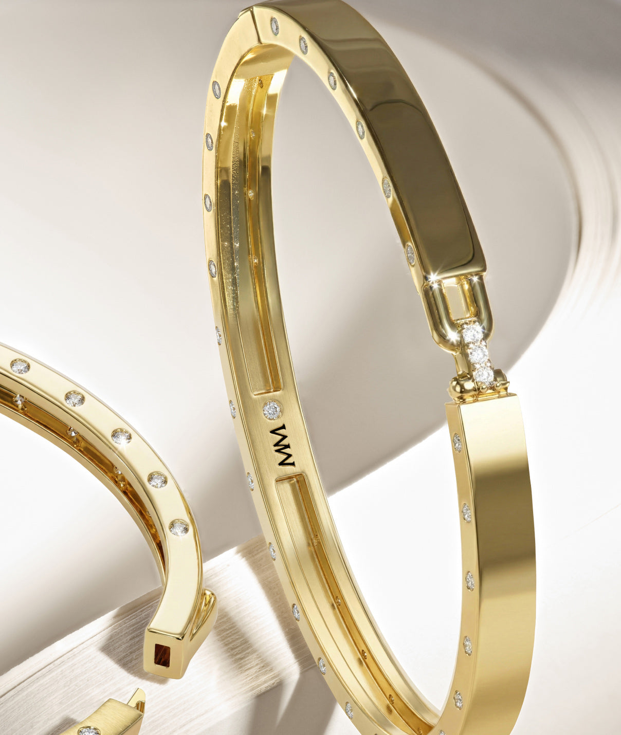 Gold bracelets with diamond accents on a light background