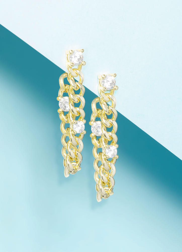 Gold chain earrings with clear stones on a blue and green gradient background