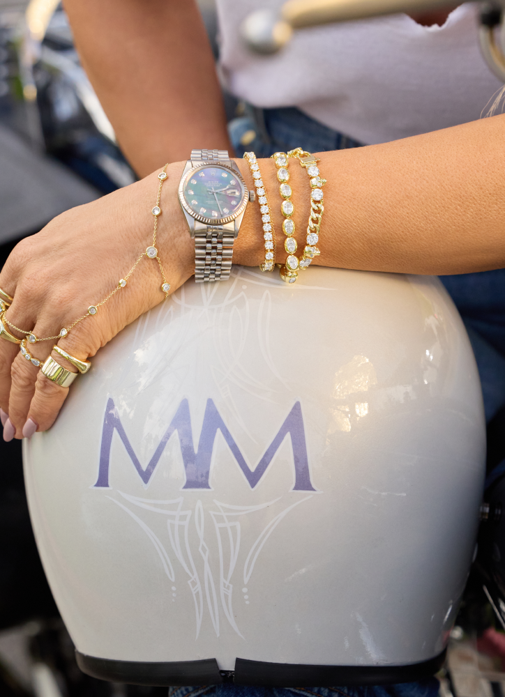 Close-up of a person's hand with jewelry on a white helmet with 'MM' branding.