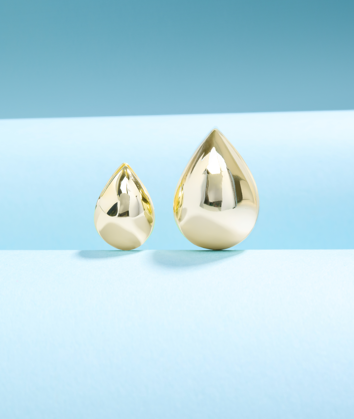 Two gold teardrop-shaped objects on a light blue background