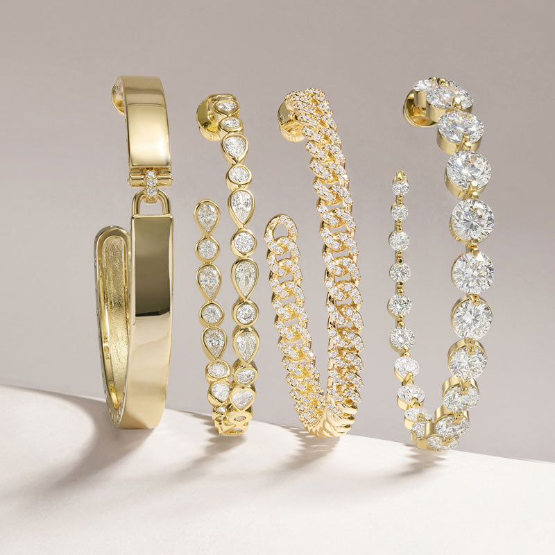 Set of gold and diamond bracelets on a neutral background