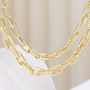 Gold chain necklaces on a white surface with a neutral background
