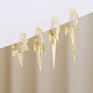 Set of gold earrings on a white and beige gradient background