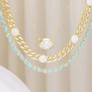 Gold chain necklace with blue and white gemstones on a beige background