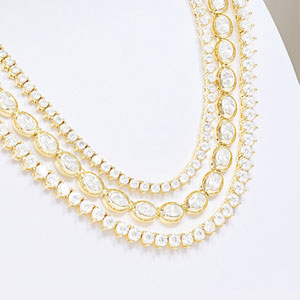 Gold necklace with clear stones on a white background